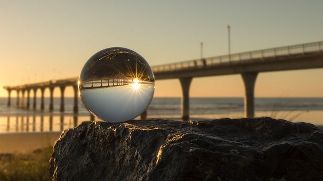 This dramatic image of a highway bridge at sunset has a crystal ball in the foreground. The bridge and the sunset are reflected upside down in the ball.